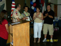 Phil receives certificate. Dad, Mom and Stepdad stand with him.